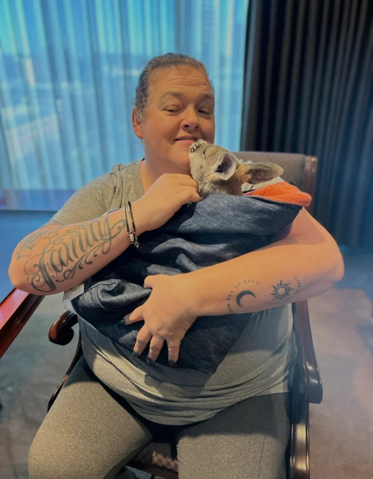 Woman cuddling baby kangaroo in blanket